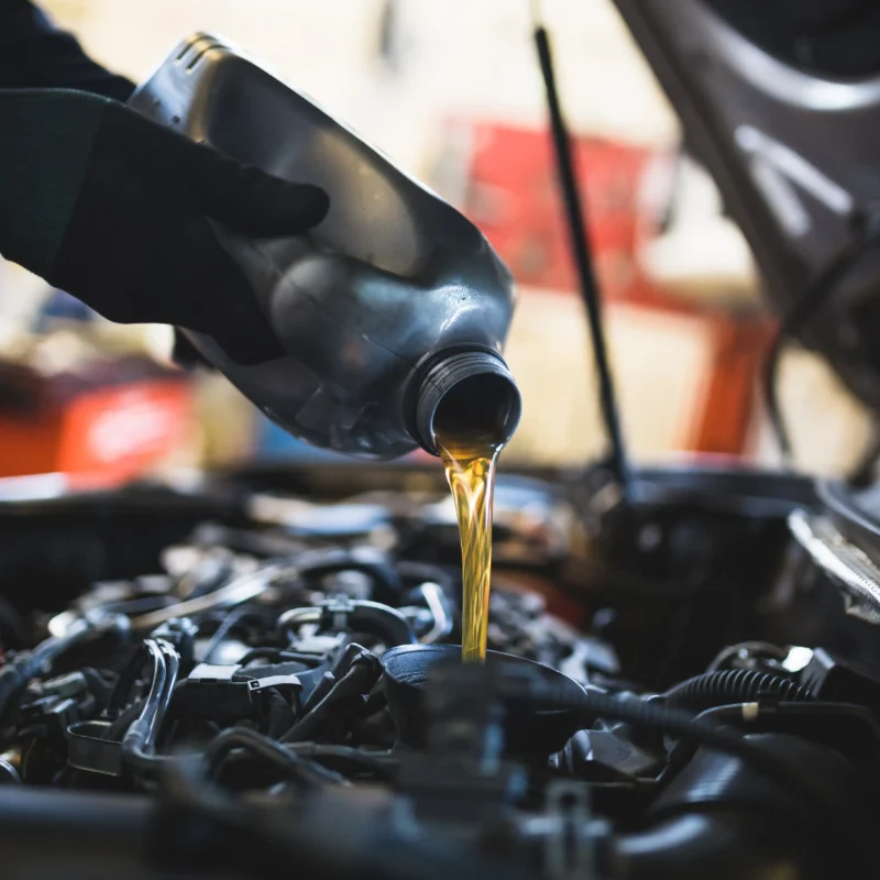Fresh motor oil being poured into a car engine