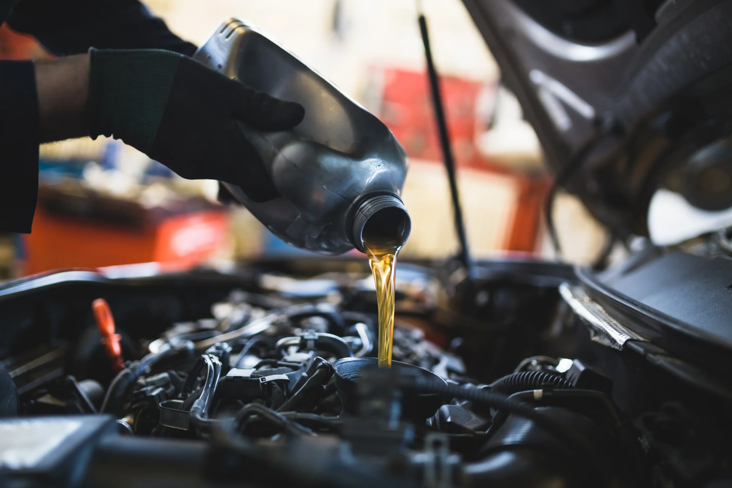 Fresh motor oil being poured into a car engine